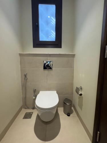 a bathroom with a white toilet with a window at Beach house بيت البحر in As Sīfah