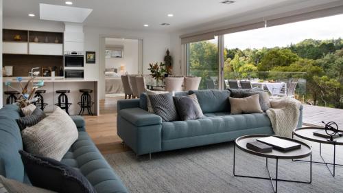 a living room with a blue couch and a kitchen at Province Lake House in Daylesford