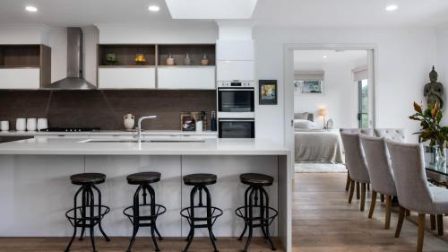 a kitchen with a counter and bar stools at Province Lake House in Daylesford