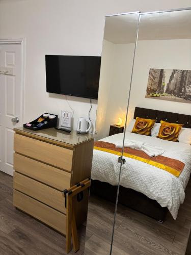 a bedroom with a bed and a desk with a television at Comfortable Ensuite Rooms and Ample Street Parking in Doncaster