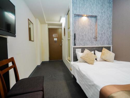 ein Hotelzimmer mit einem Bett und einem Fernseher in der Unterkunft Hotel Areaone Okayama - Vacation STAY 32493v in Okayama
