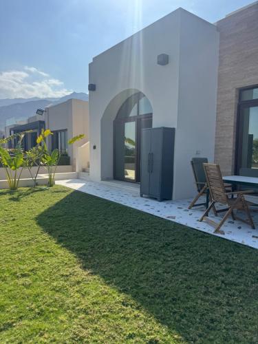 a patio with a table and chairs on a lawn at Beach house بيت البحر in As Sīfah
