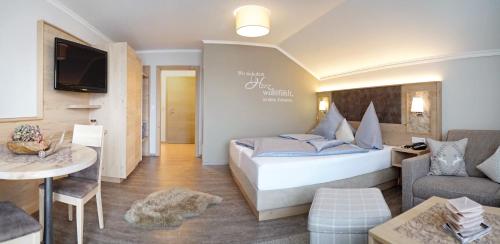 a hotel room with a bed and a living room at Fichtenwald-Ihr Boutique I Glück`s Hotel in Bad Füssing
