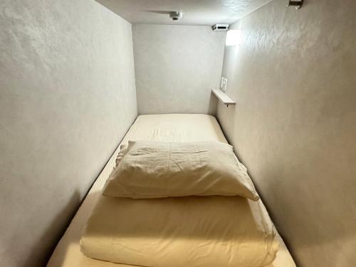 a small room with a small bed in it at HOTEL minimumms女性専用カプセルホテルWomen only hotel in Naha