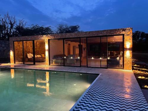 une maison avec une piscine devant dans l'établissement Kesar Farm House on the Lake, à Udaipur