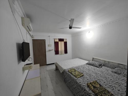 a bedroom with two beds and a tv in it at Kulswami Cottage Alibag in Alibaug