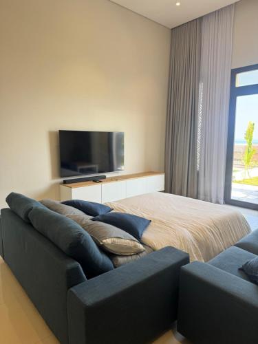 a bedroom with a couch and a flat screen tv at Beach house بيت البحر in As Sīfah