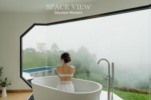 a woman sitting in a bath tub looking out a window at Sky View Mon Jam in Chiang Mai