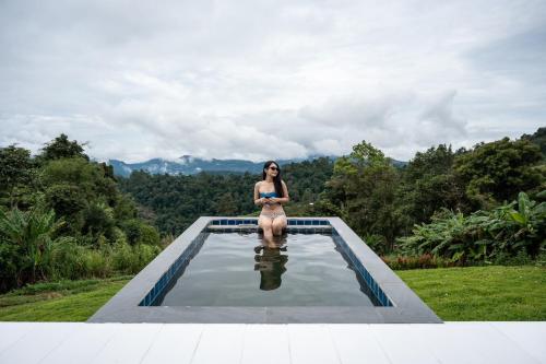 a woman sitting on the edge of a swimming pool at Sky View Mon Jam in Chiang Mai