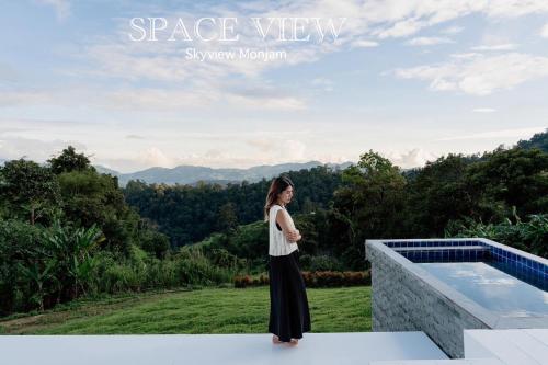 a woman standing on a ledge next to a swimming pool at Sky View Mon Jam in Chiang Mai