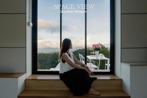 a woman sitting in a window with a view at Sky View Mon Jam in Chiang Mai