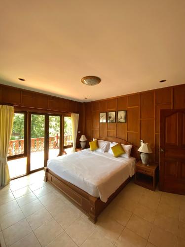 a bedroom with a large bed and a balcony at Baan Laem Noi Villa's in Mae Nam