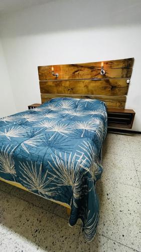 a bed with a blue comforter and a wooden headboard at Casa Dahlia Querétaro in Querétaro