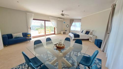 a living room with a glass table and blue chairs at Grace Space in Plattekloof in Cape Town