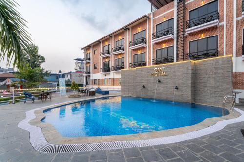 a swimming pool in front of a building at Chitwan Midtown Hotel in Bharatpur