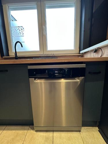 a stainless steel dishwasher under a counter with two windows at The175 work or holiday home in Comines