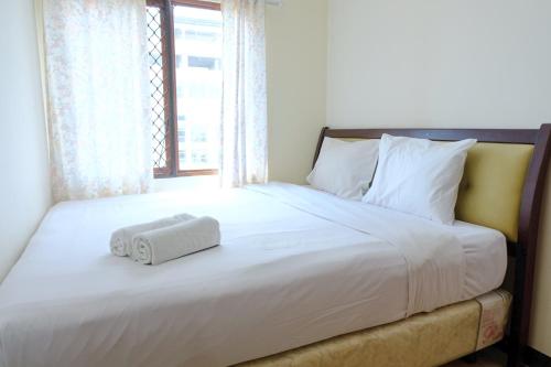 a white bed with a box on it with a window at Scenic 2BR at Grand Setiabudi Apartment By Travelio in Bandung