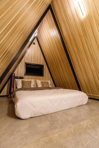 a large bed in a room with a wooden wall at The Dune Retreat by StayJadePoolTwin VIllas in Devanahalli-Bangalore