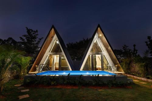 a house with a swimming pool at night at The Dune Retreat by StayJadePoolTwin VIllas in Devanahalli-Bangalore