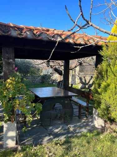 a picnic table and a bench under a roof at As Tres Irmas in Candeleda