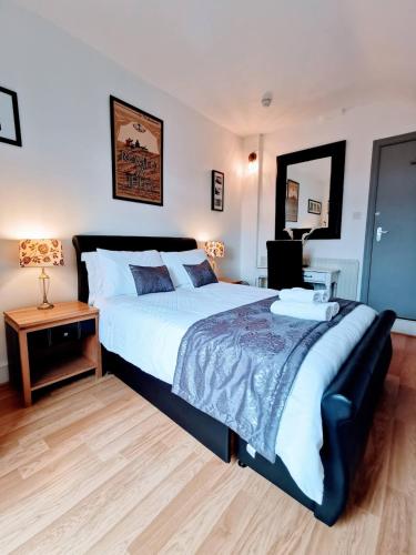 a bedroom with a large bed and a mirror at Victoriana Duplex Apartment in Stratford-upon-Avon