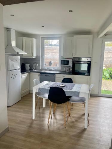 une cuisine blanche avec une table et des chaises blanches dans l'établissement Maison chaleureuse bord de mer, à Plérin
