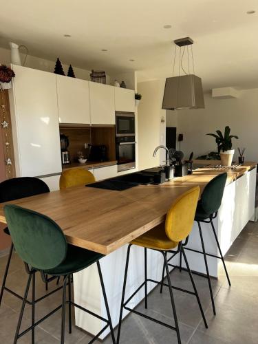 une cuisine avec une table en bois et des chaises jaunes dans l'établissement Maison la Cocagne de la Sainte Baume, à Nans-les-Pins
