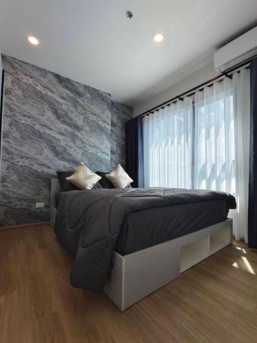 a bedroom with a large bed with a stone wall at 1 Bedroom condo next to Central Hatyai in Hat Yai