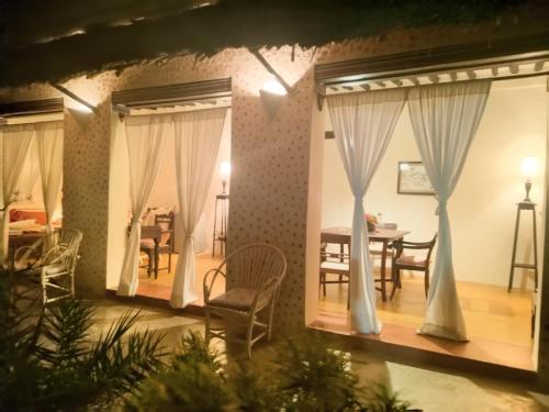 een woonkamer met een tafel, stoelen en gordijnen bij Madakani House in Lamu