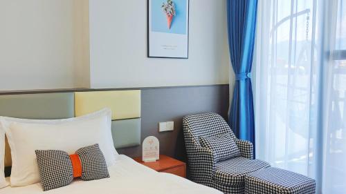 a bedroom with a bed and a chair next to a window at 大理顾里海景别墅Dali Guli Sea View Villa Hotel in Dali