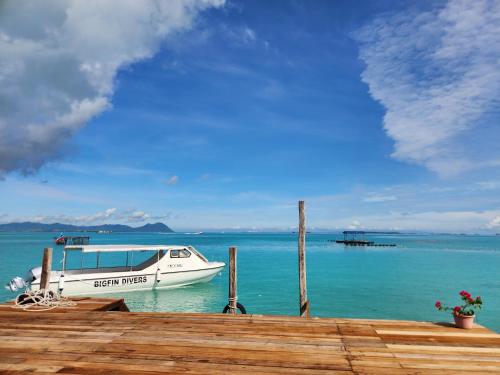 a boat sitting on the water next to a dock at Bigfin water bungalow in Semporna
