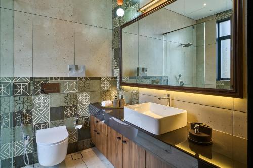 a bathroom with a sink and a toilet and a mirror at SaffronStays Eldora by the Lake in Matheran