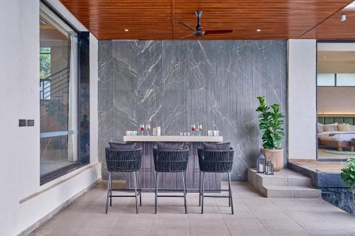 a bar in the side of a house with stools at SaffronStays Eldora by the Lake in Matheran