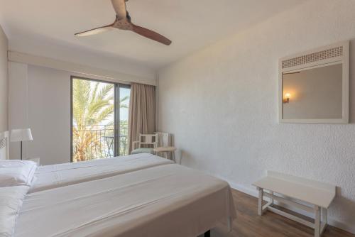 een witte slaapkamer met een bed en een raam bij Hostal Sa Baronia in Banyalbufar