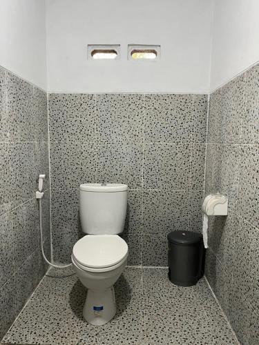 a bathroom with a toilet in a tiled room at PANORAMA BUNGALOWs in Tetebatu