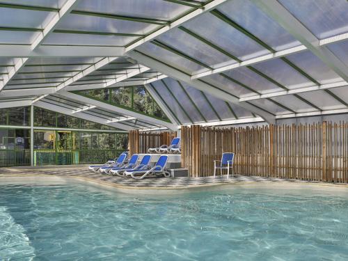 - une piscine avec des chaises bleues et une piscine dans l'établissement Domaine Résidentiel de Plein Air Les Dunes, à Longeville-sur-Mer