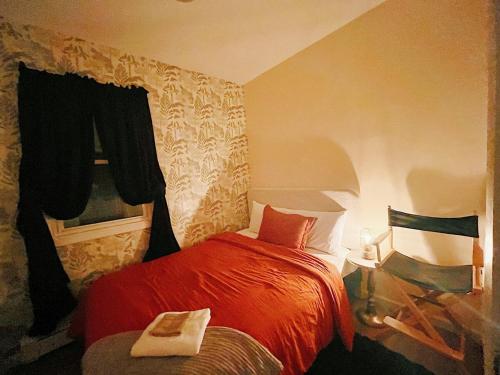 a bedroom with a red bed and a chair at 3 bdrm stay! Trippy King Suite by Dwtwn Nwk in Newark