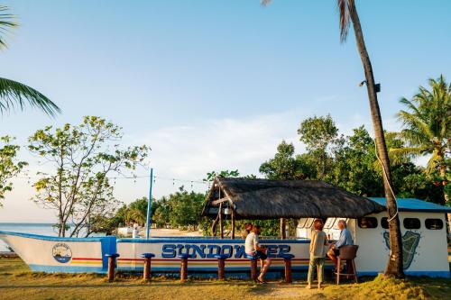 a boat on the beach with people sitting at a table at Polaris Beach and Dive Resort Inc in Loon