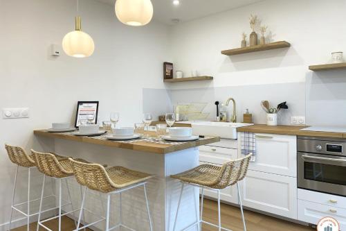 une cuisine avec un bar avec des tabourets et un évier dans l'établissement Le Petit Palais - 50m Plage - Vue mer et campagne, à Tourgéville