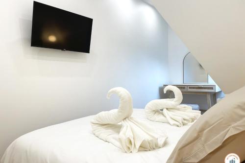 2 cygnes assis au-dessus d'un lit dans l'établissement Le Petit Palais - 50m Plage - Vue mer et campagne, à Tourgéville