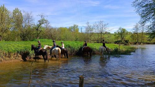 a group of people riding horses in the water at Le moulin de vaux in Nochizé