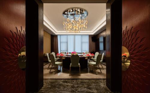 a dining room with a table and chairs and a chandelier at Zhuhai Palm Spring Hotel in Zhuhai