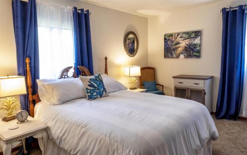 a bedroom with a large white bed with blue curtains at Sea La Vie in Fort Bragg