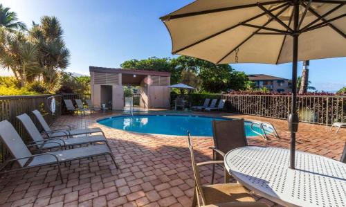 patio con tavolo e ombrellone accanto alla piscina di Perch - Maui Vista 3114 a Kihei