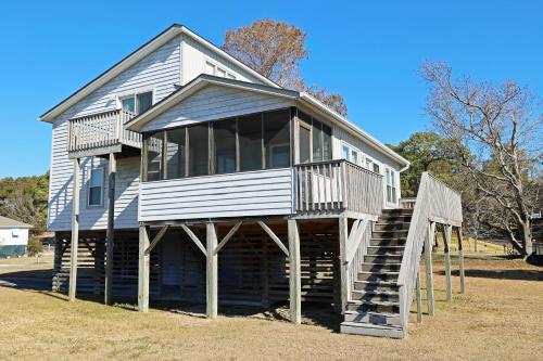 a house on wooden posts with a staircase in front at CH103- Beach Retreat in Kill Devil Hills