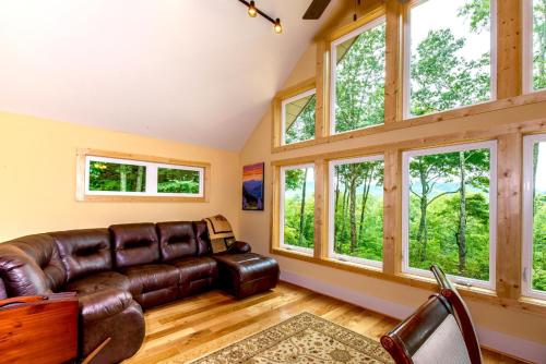 a living room with a leather couch and windows at Sweet Refrain in Pisgah Forest