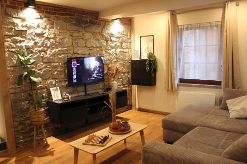 a living room with a couch and a stone wall at Le Gite des Croisettes in Les Croisettes