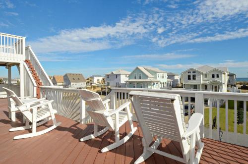 a deck with white chairs on a balcony with houses at KH4004- Paradise in Kitty Hawk