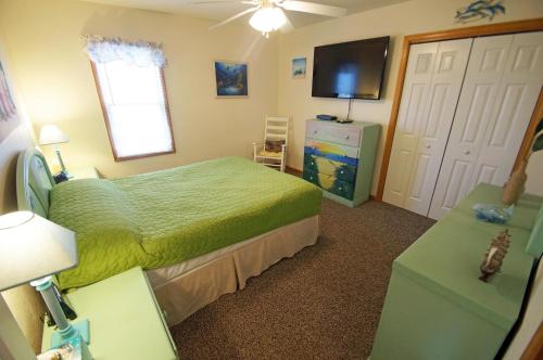 a bedroom with a green bed and a television at KH4004- Paradise in Kitty Hawk