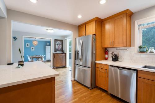 a kitchen with wooden cabinets and a stainless steel refrigerator at Perch - Shoreline Gathering Spot in Shoreline